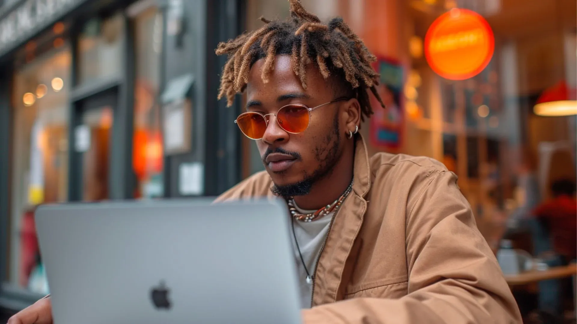 A man sat outside a coffee shop on his laptop